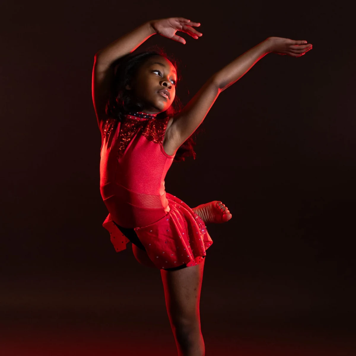 Young dancer performing under dramatic red stage lighting