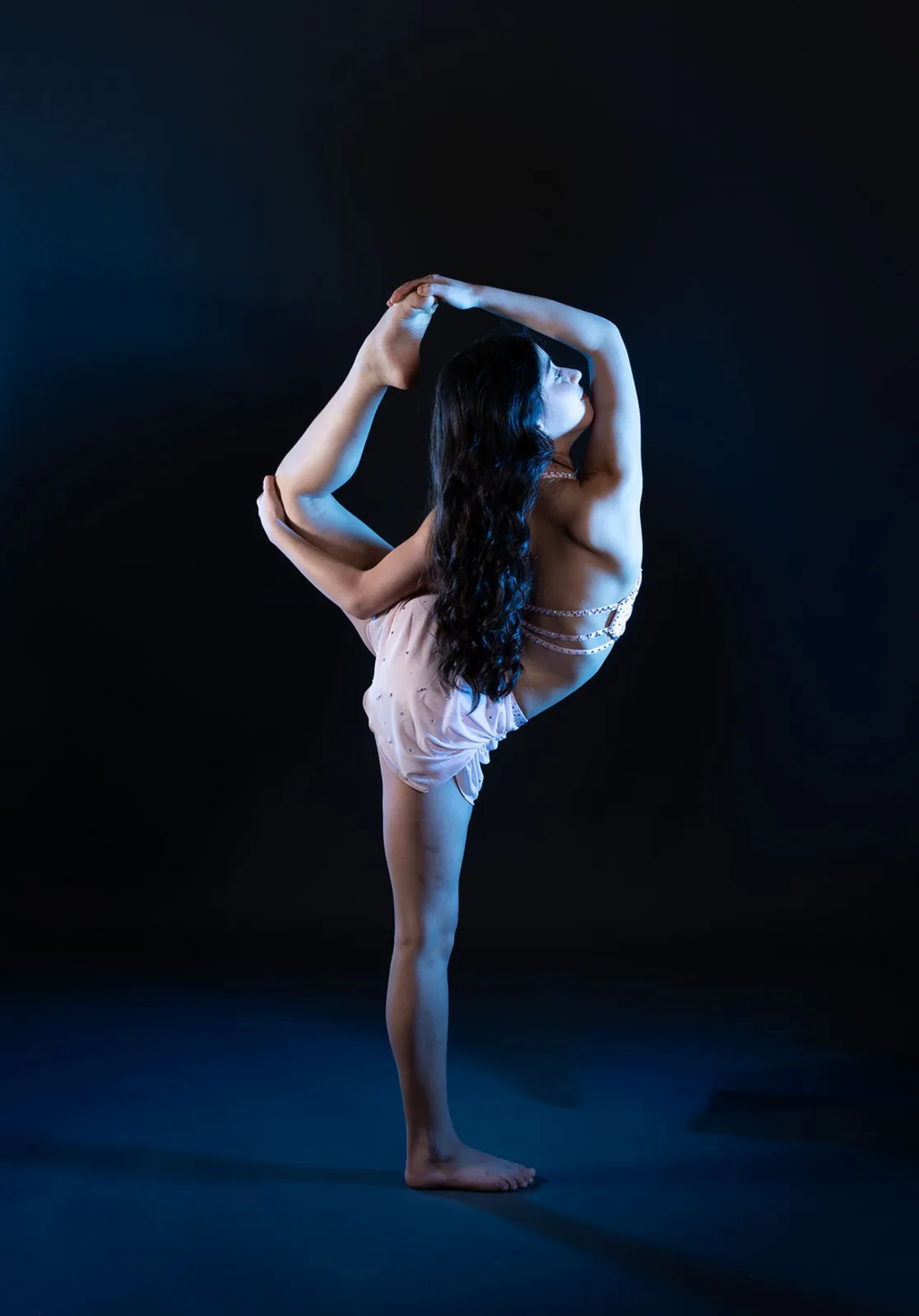 Advanced dancer performing under blue stage light