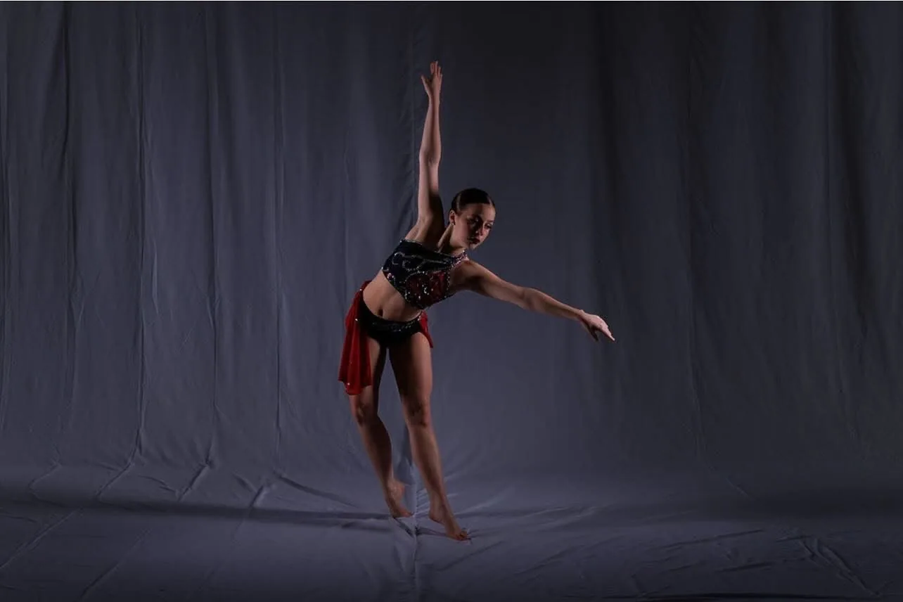 Dancer performing under dramatic dark stage lighting