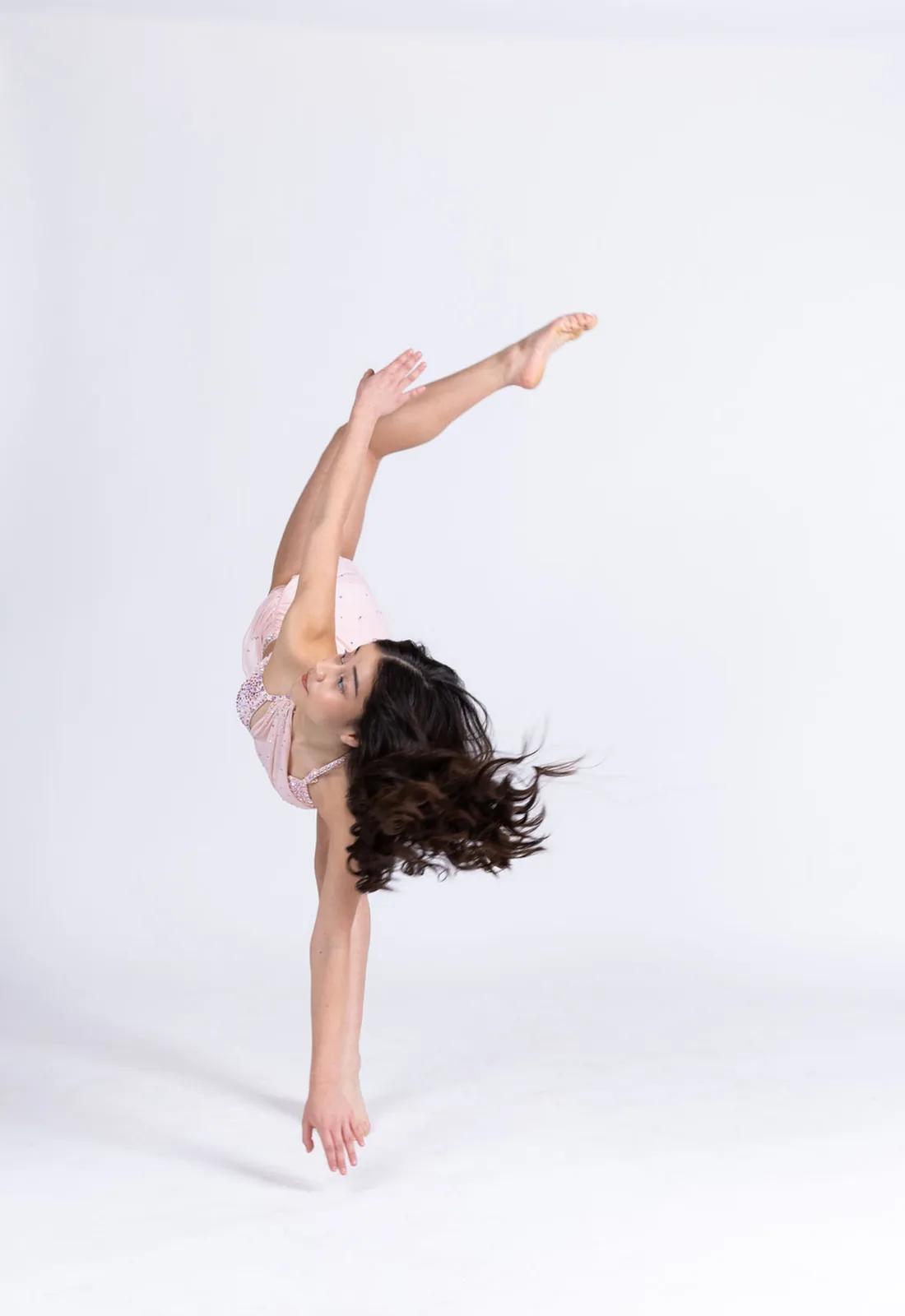 Dancer in a pale pink costume performing an acrobatic extension