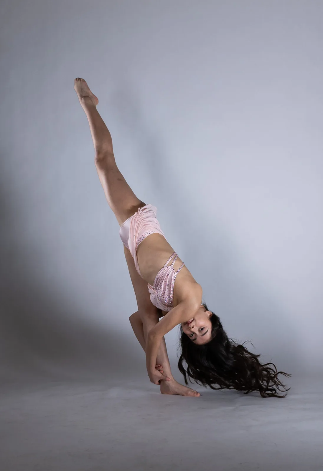 Dancer in a pale pink costume performing an inverted extension
