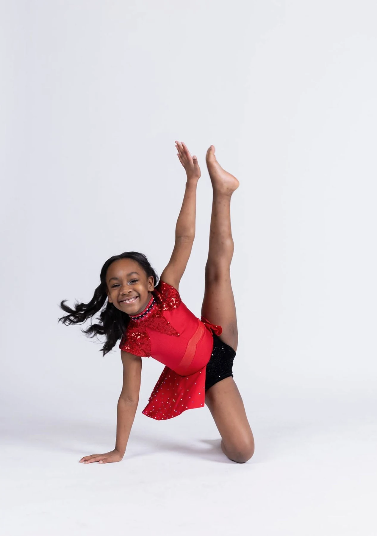 Young dancer in a red costume demonstrating flexibility