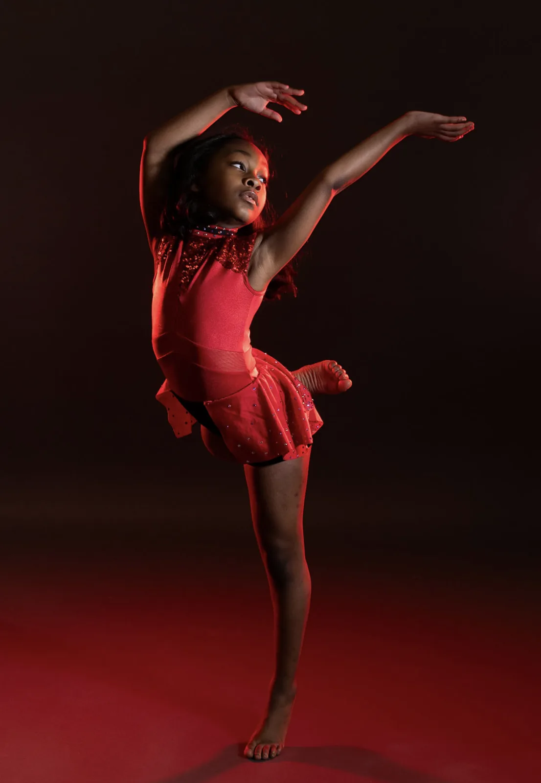 Young dancer performing under dramatic red stage lighting