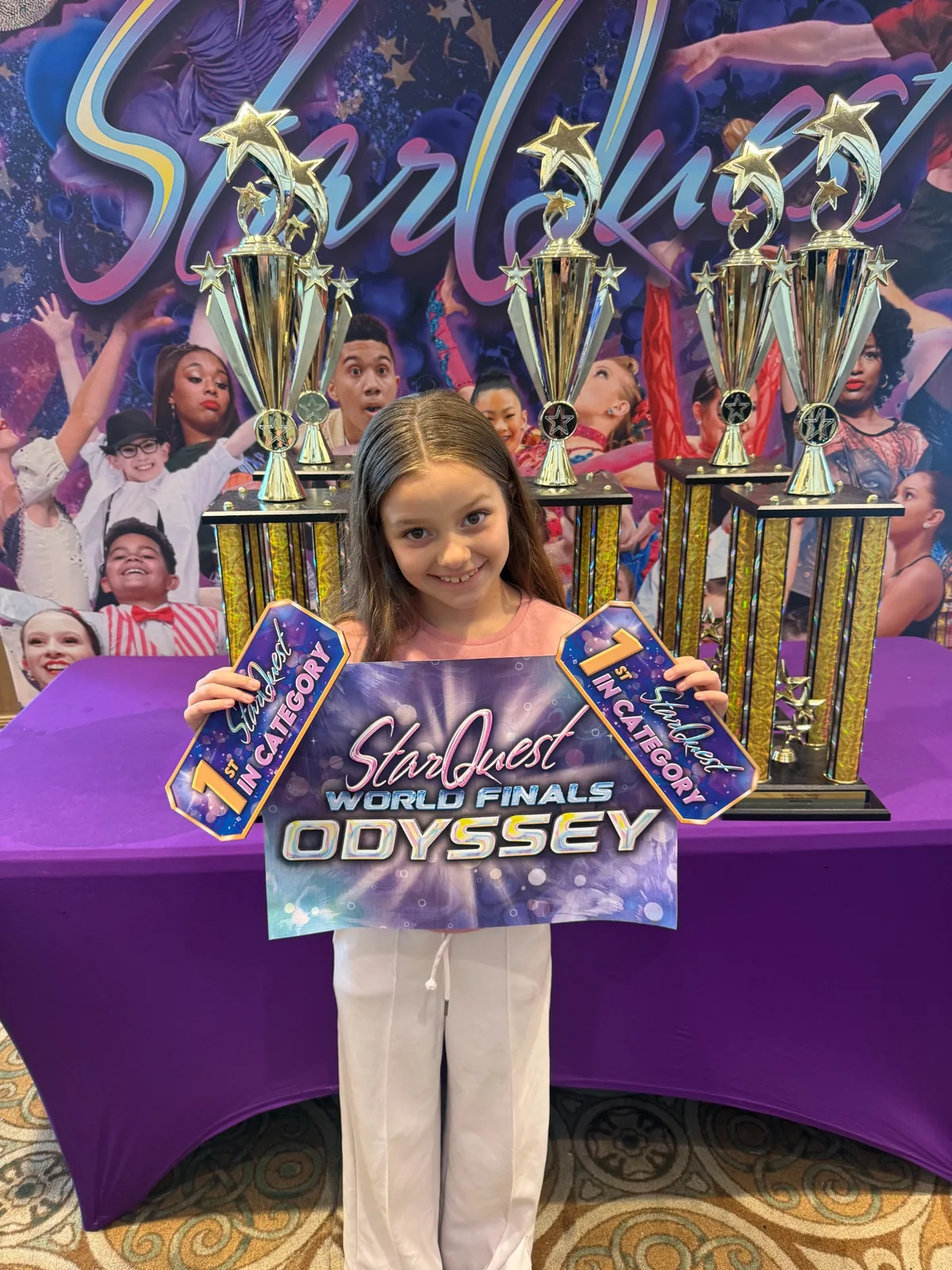 Young student holding competition awards in front of trophies